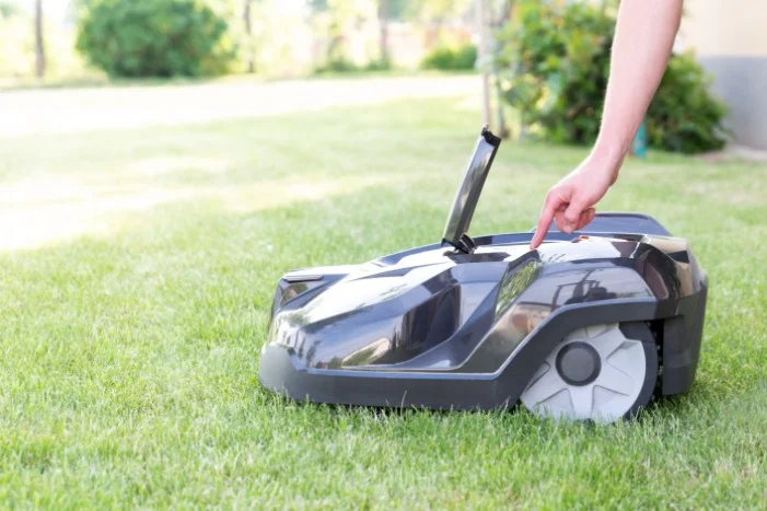 Person startet Mähroboter